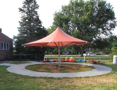Image of an ubrella style shade structure over tricycle course.
